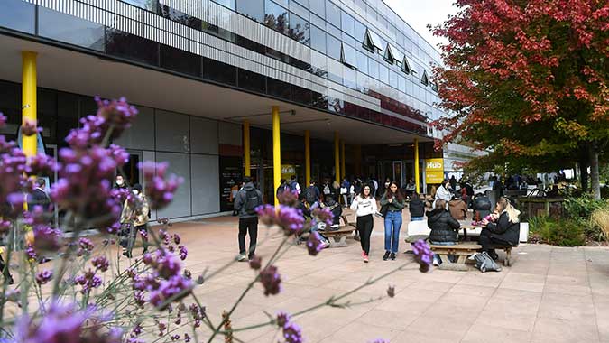 Students walking past the Hub with blossom trees