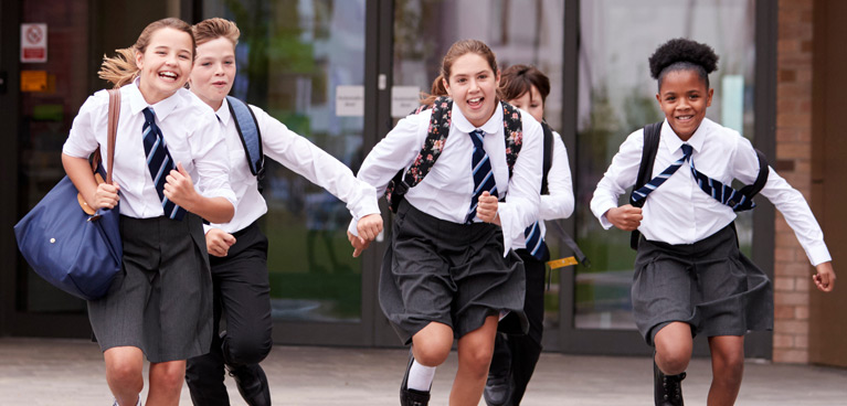 Schoolchildren in uniform running and laughing