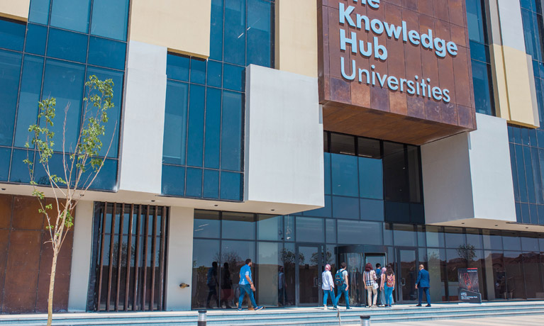 People walking into the Egypt Knowledge Hub, a modern glass fronted building.