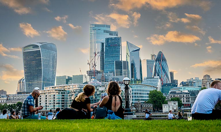 People sat outside with the london skyline in front
