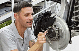 A man in a grey t shirt working on an engine.