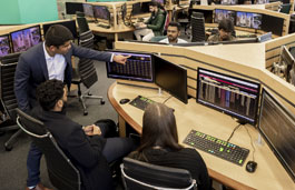 A lecturer assisting two students on the Trading Floor