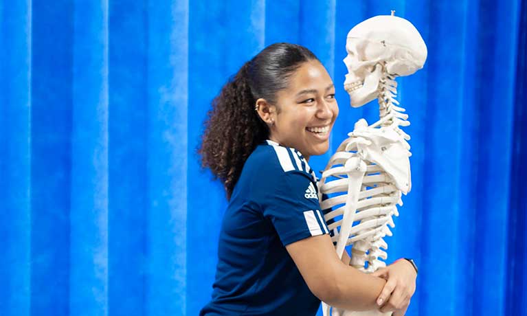student smiling holding a skeleton