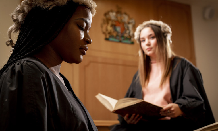 2 female students dressed in court outfits in moot room 