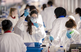 Students wearing white coats and working in the SuperLab.