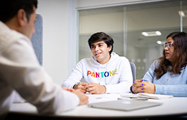 Two students discussing something with another person looking towards them