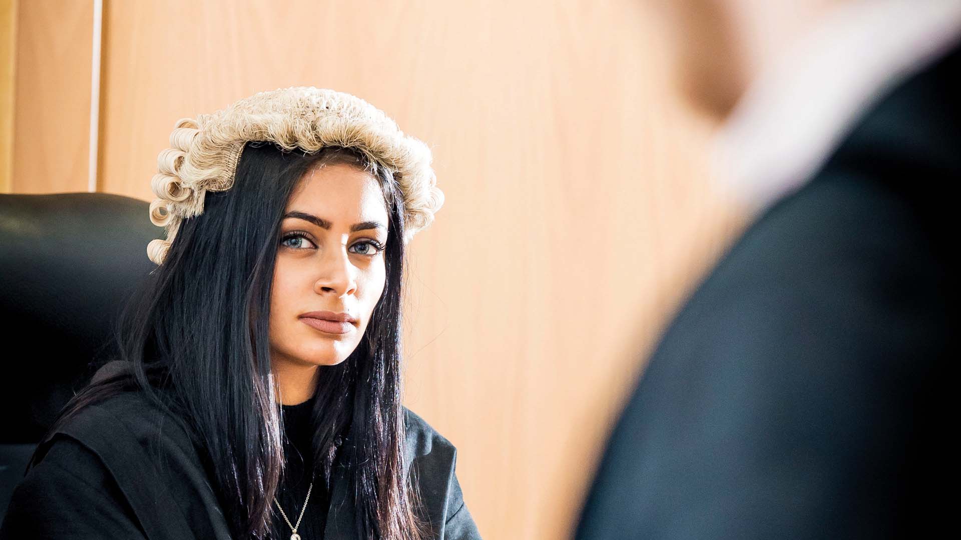 A student using the mock courtroom, wearing a court wig.