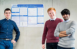 Three students standing in front of a poster.