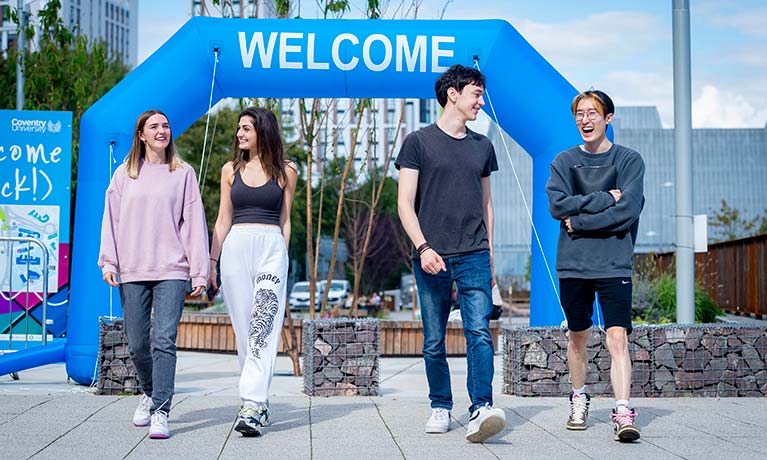 Students in front of a welcome sign on campus