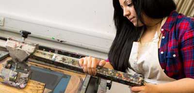Student using a printing press in a design studio