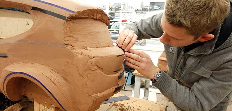 Student sculpting a clay model vehicle