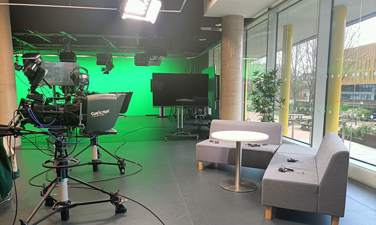 Shot of TV studio with couches in foreground and green screen in background