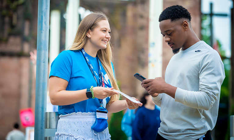 A Students' Union rep chatting to another student outside on campus.