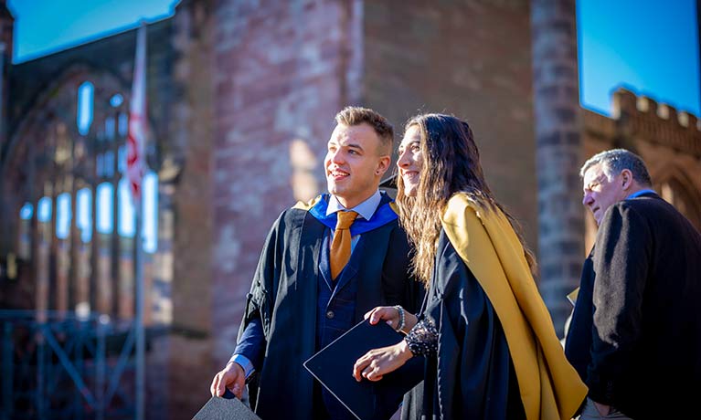 male and female graduates outside the cathedral posing for a picture