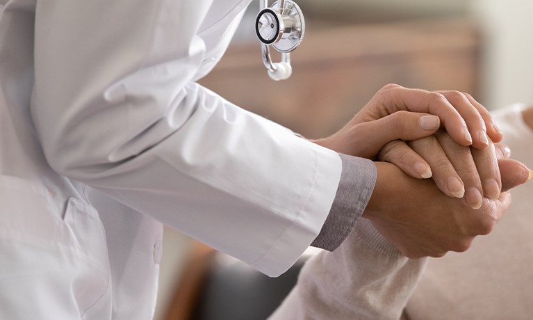 healthcare professional holding the hand of a patient