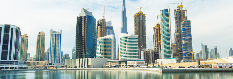 View of city skyscrapers by a waterway in Dubai.