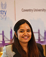 Portrait of Sadia Afrin Prova smiling with a Coventry University branded poster in the background