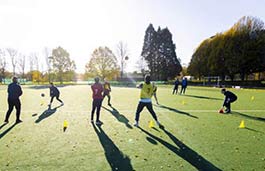  Students training on a football pitch in evening sun 