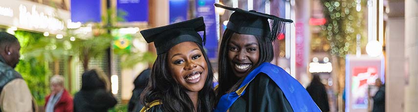 Two female graduations in their gown smiling