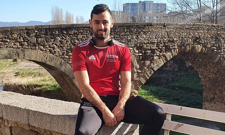 Aleksandar Dinkov in a red t-shirt with a bridge in the background