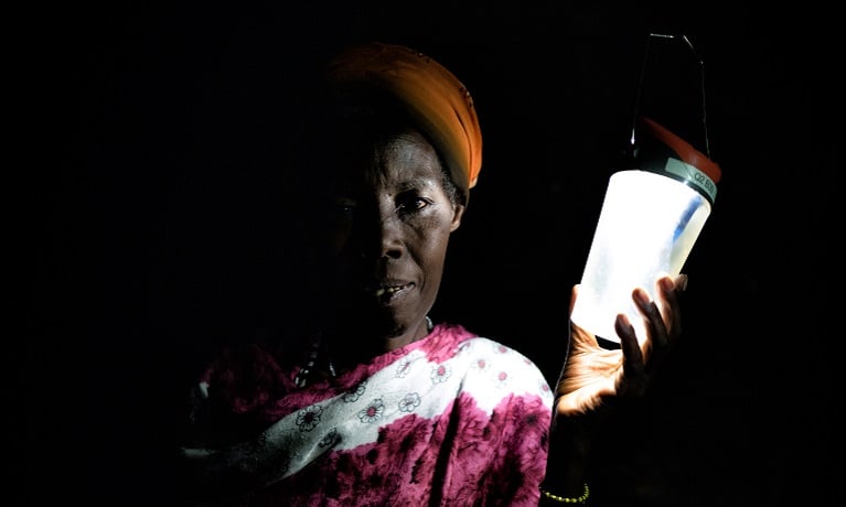 Woman in Nyabiheke refugee camp, Rwanda, holding a solar-powered lantern