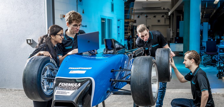 Group of young students looking at an F1 car prototype