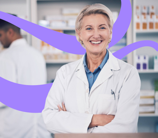 A person wearing a lab coat standing with arms crossed in a pharmacy or medical workspace.