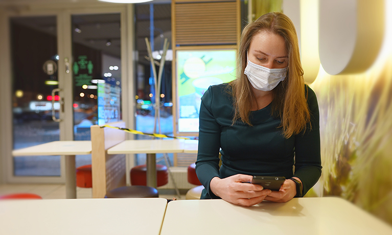 A lady sat in a cafe wearing a Covid mask