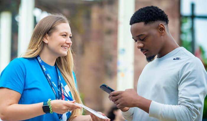 student advisor showing a student a leaflet in the catherdral grounds