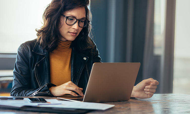 Female sat at a table typing on a laptop