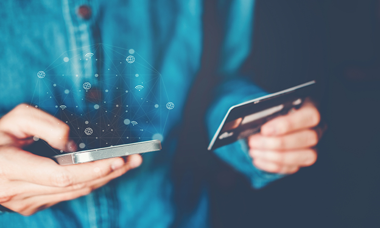 A person holding a credit card in one hand and a mobile phone in the other