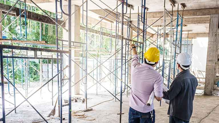 two construction workers looking at a structure