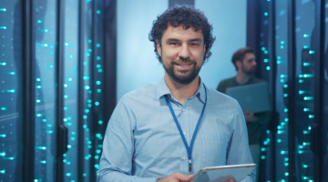 Man in blue shirt holding ipad in front of a data centre