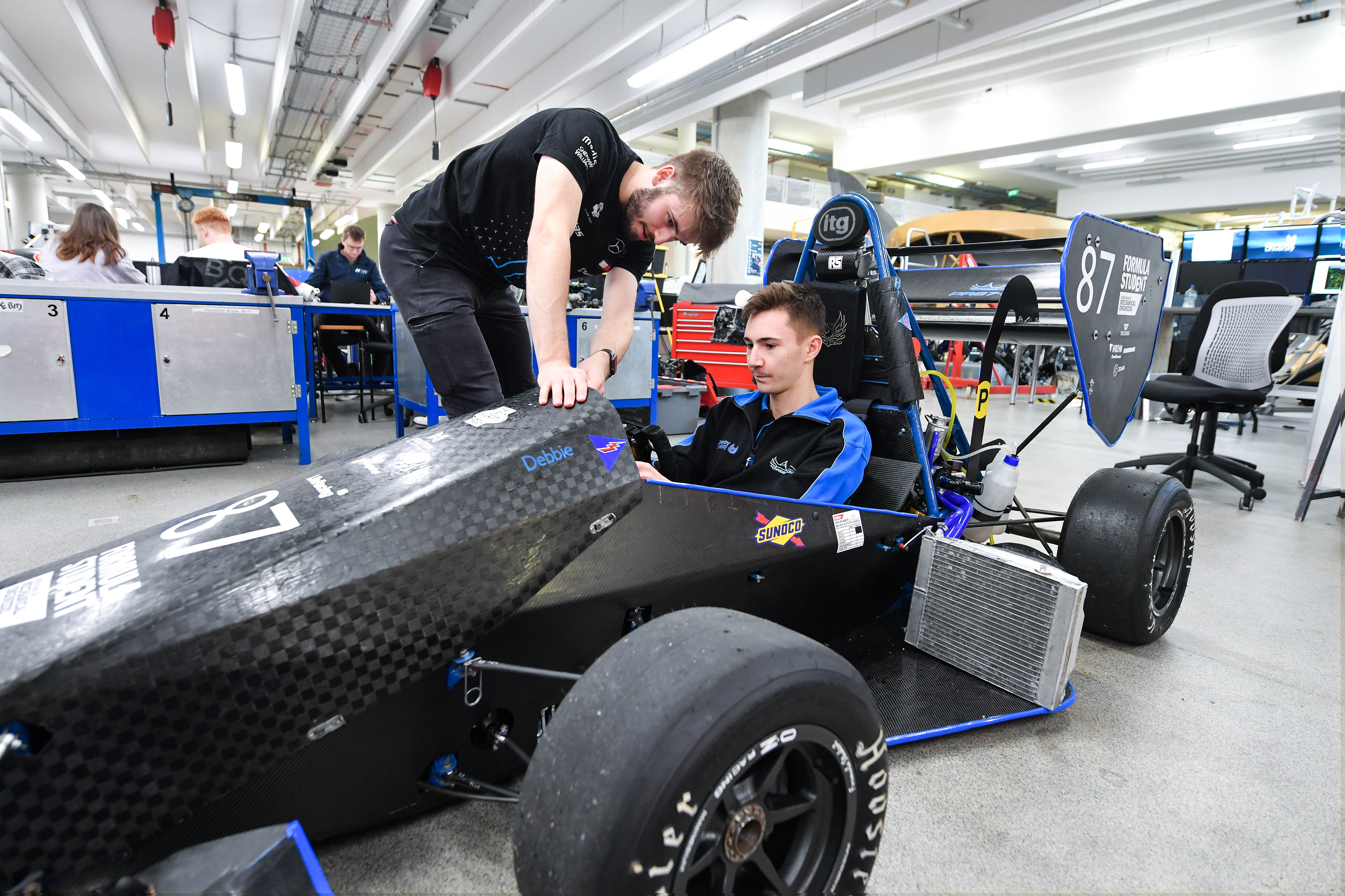 two students examining a motorsport car at Coventry Univeristy