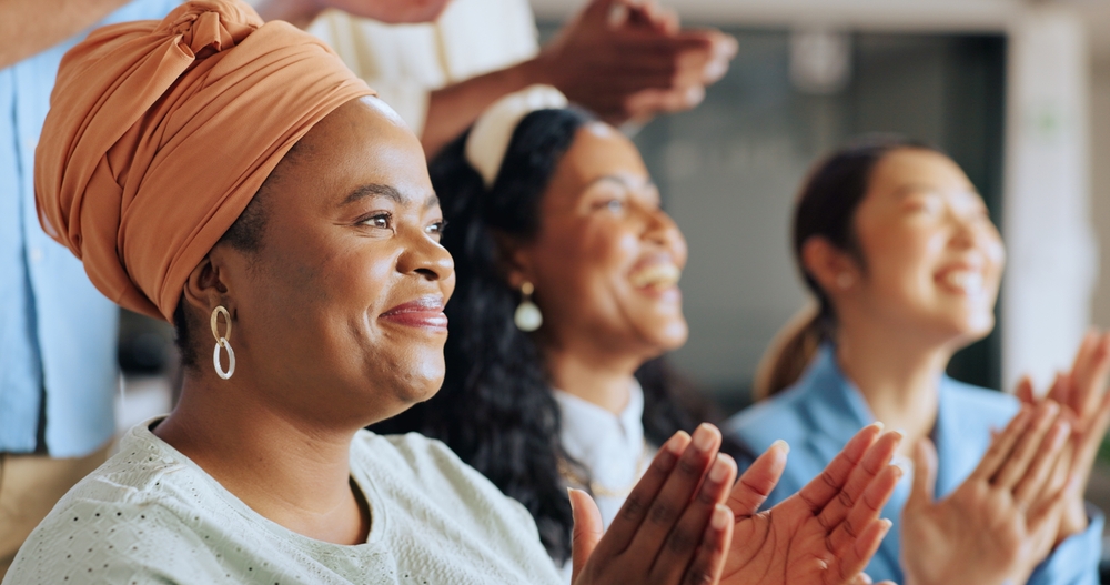 Small group of black women clapping and smiling