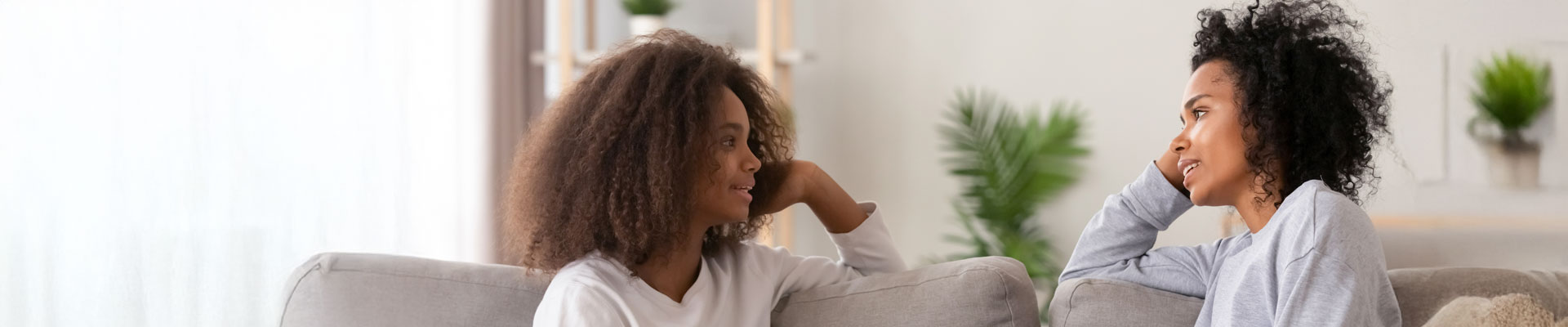 mother and daughter are sitting on a sofa and are discussing university options