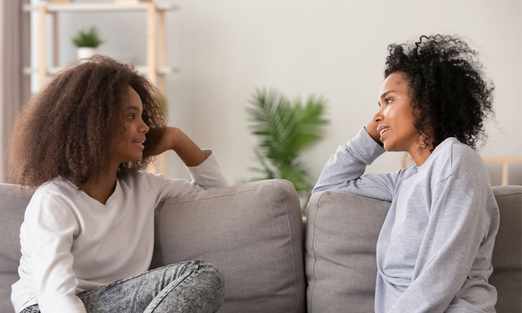 mother and daughter are sitting on a sofa and are discussing university options