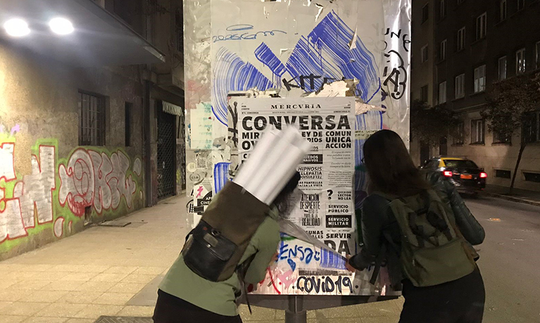 Two students gluing a poster to a billboard