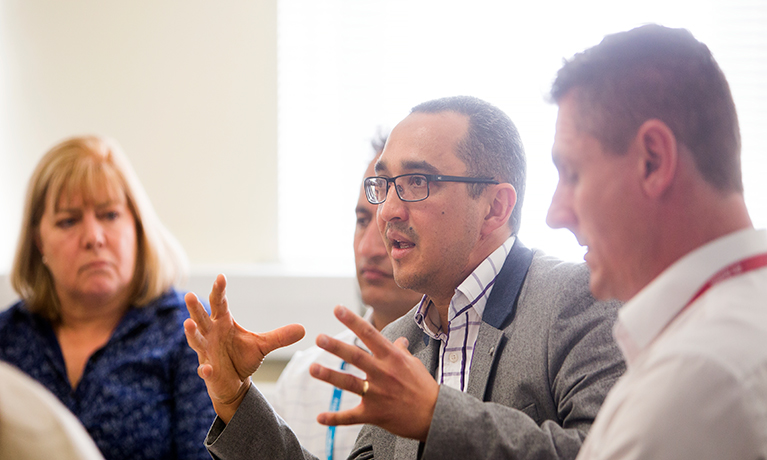 Man speaking with hands raised to a group
