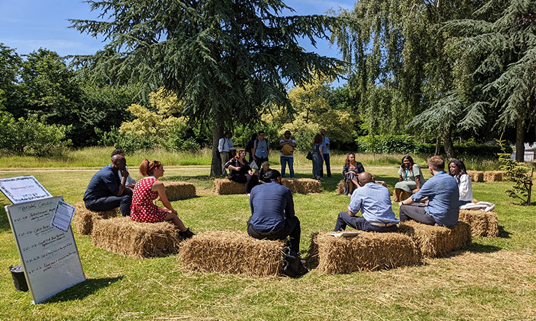 People sat in a circle talking on straw bales