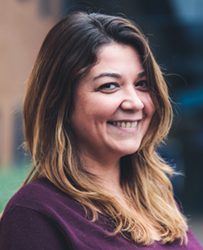 Neslihan Ozfaris smiling in close-up portrait with an out of focus blurred background