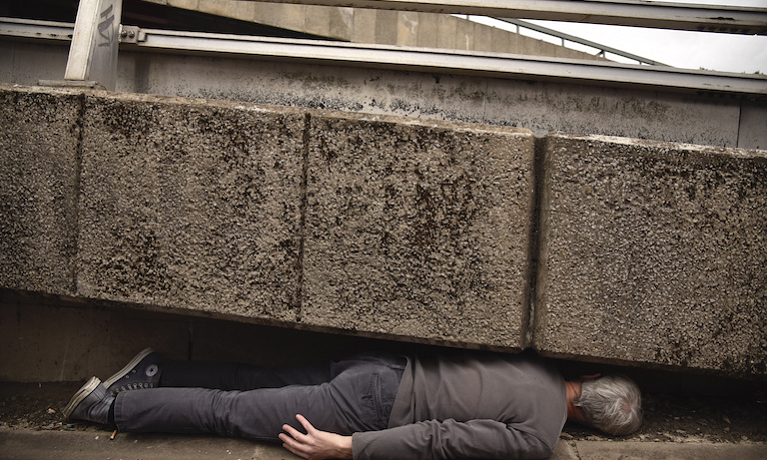 man lying under concrete highway