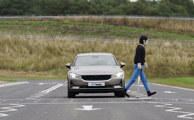 A mannequin crossing a road in front of a car