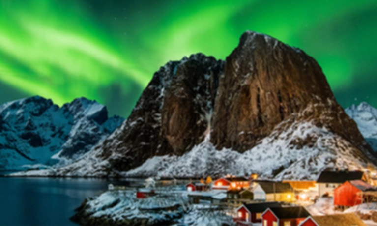 the northern lights projecting green light over a snowy mountain landscape