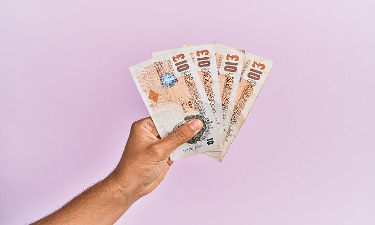 A hand holding British 10 pound notes