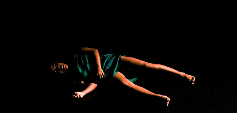 A woman laying down surrounded by a dark background