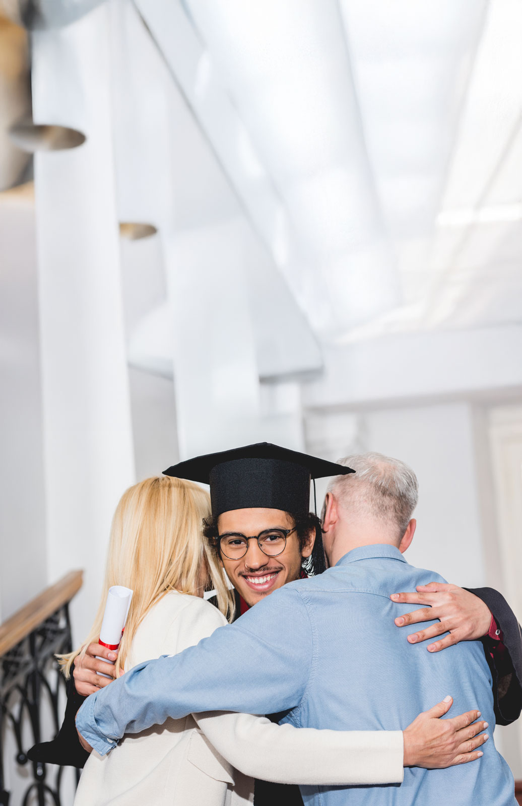 Parents hugging their child gradiating university