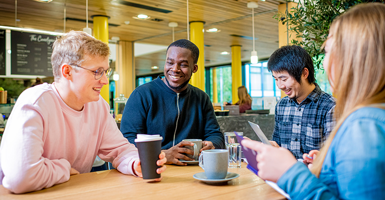 Students sat at a table together with cups of coffee