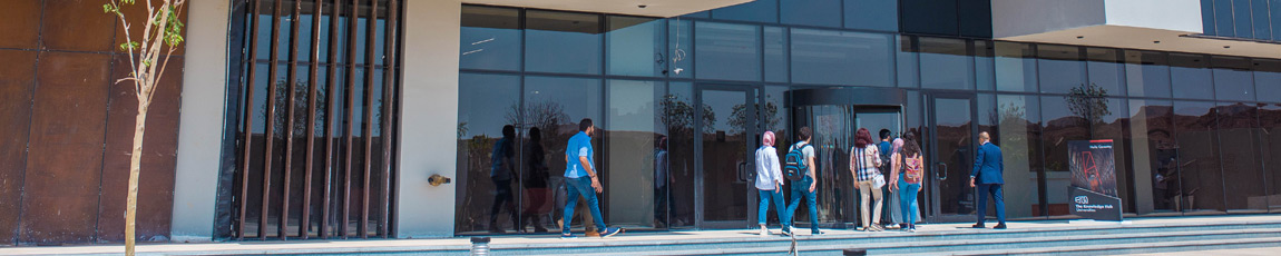 People walking into the modern Knowledge Hub Universities building in Egypt.