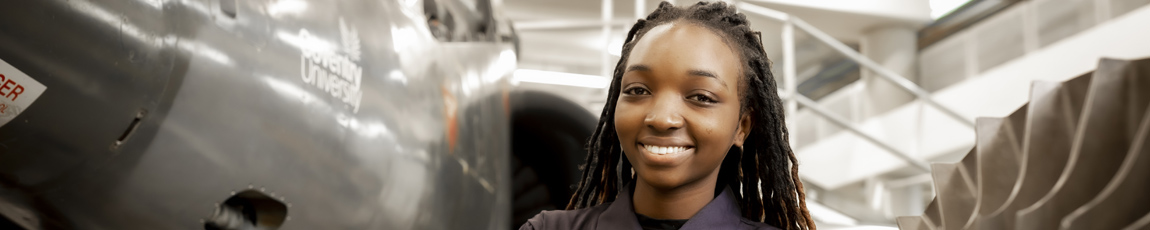 An international student working on a Harrier Jet, smiling at the camera.